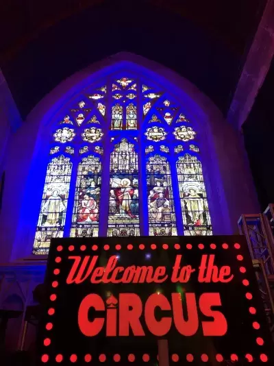 Welcome to the circus sign with stained glass window in the background